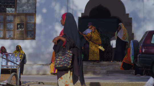 非洲坦桑尼亚街头行人，传统服饰与建筑背景