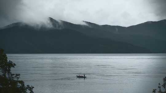 云南高原湖泊泸沽湖阴雨天乌云湖面小舟游船