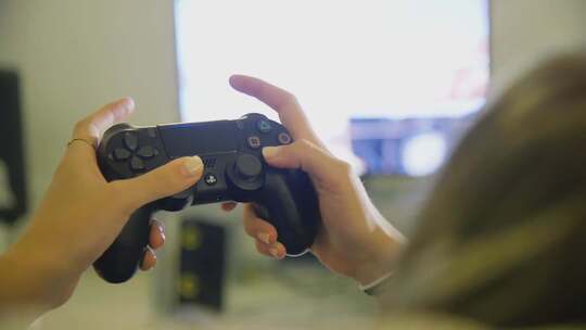 女孩在家使用黑色PS4双摇杆游戏手柄玩游戏视频素材模板下载