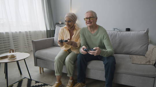 老年夫妻坐在沙发上打游戏