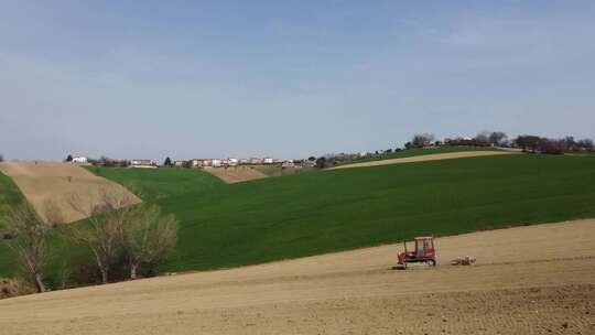 农业公司红色拖拉机下坡耕作和准备农业有机土壤的空中视频素材模板下载