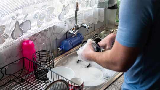 一个家伙在双厨房水槽里洗碗的延时镜头。视频素材模板下载