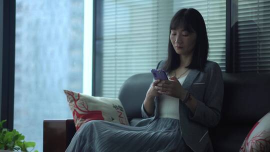女人坐在沙发玩手机视频素材模板下载