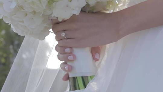 带着戒指和花束的新娘之手