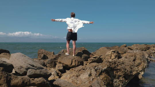 男人在海边岩石上看海景