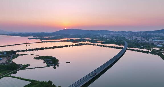 航拍夕阳下穿过鄱阳湖的乡间高速公路