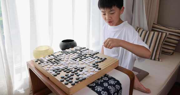 可爱的男孩在窗边下围棋