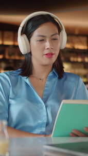 亚洲女人在咖啡馆听音乐和看书