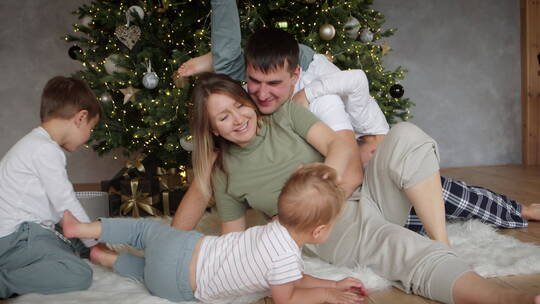 在圣诞树旁和孩童玩耍的父母