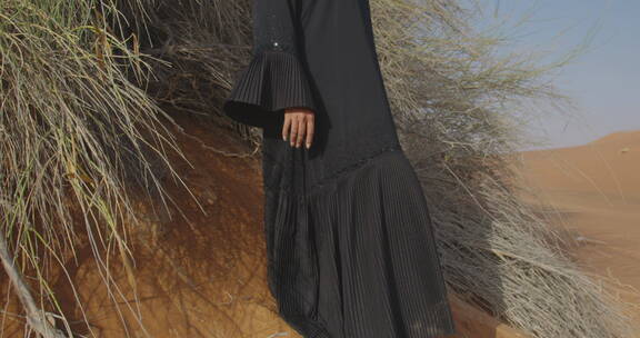 穆斯林女人穿着传统服装站在沙漠拍照
