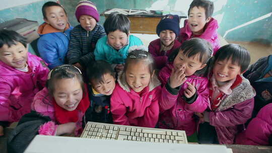 贫困地区的小学生在破旧的教室上课孩子们围绕电脑开心学习