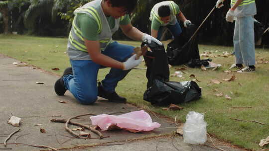 亚洲人在城市公园把垃圾扔进垃圾袋