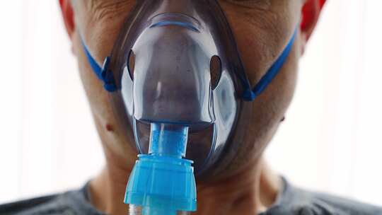 戴雾化器面罩呼吸的不健康男子在家庭健康医