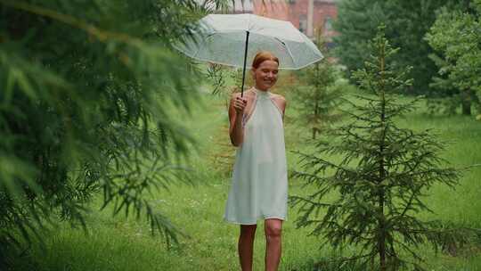 雨天，年轻女子撑着伞在郁郁葱葱的绿色公园