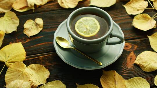 一杯柠檬茶和许多金黄色的树叶