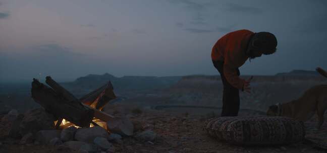 一个人跪在沙漠里和狗玩耍