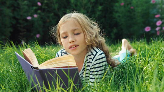 女孩趴在草地上读书视频素材模板下载