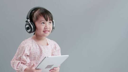 一个小女孩戴着耳机听音乐