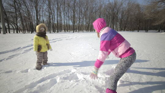 女孩和妈妈开心的在雪地里玩雪打雪仗