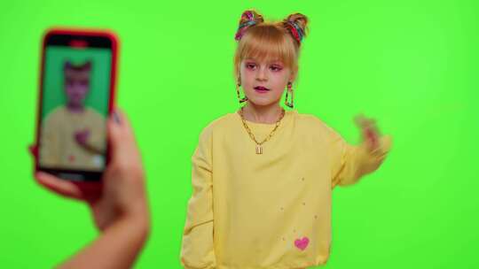 开朗有趣的小女孩孩子在相机上跳舞拍摄视频使用手机在色度键墙上视频素材模板下载