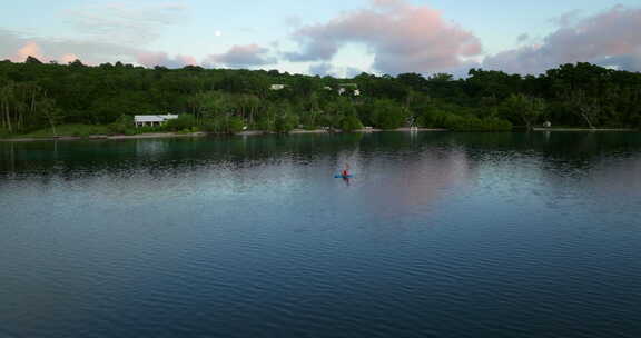 瓦努阿图莫索岛日出时一对夫妇在桨板上和皮