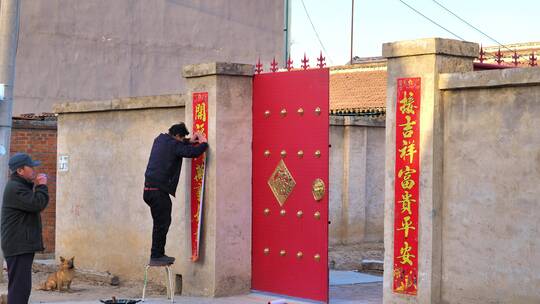 大年三十村民在给大门贴春联视频素材模板下载