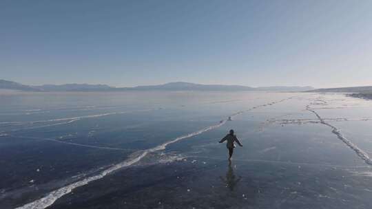 航拍女孩在新疆赛里木湖冰封蓝色湖面上行走