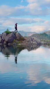 一个徒步旅行者在岩石地形上与湖中的山脉反