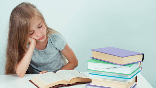女孩打哈欠并阅读一本书 