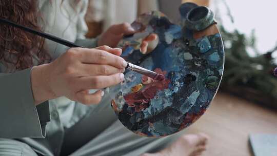 一个人拿着一个覆盖着油漆的调色板