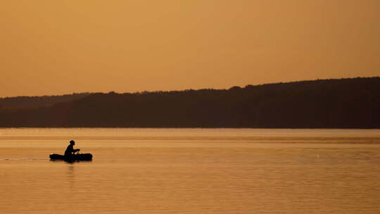 船上渔夫的剪影。日落时从船上在湖上钓鱼视频素材模板下载