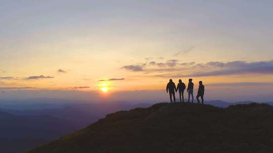 夕阳下登顶山巅团队合作企业精神励志风景