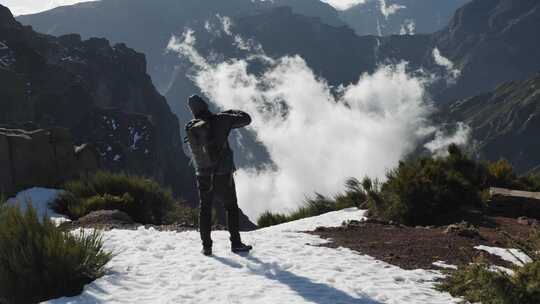 男子站在雪山上拍摄山脉
