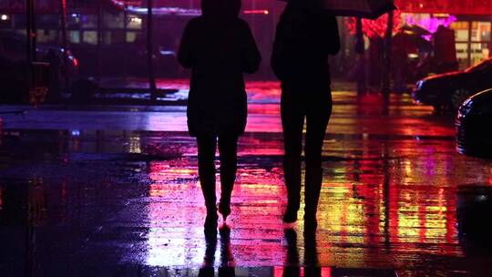 夜晚雨中灯光下行走的行人与车辆