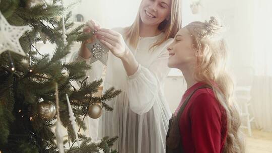 妈妈和女儿在圣诞树上挂装饰品
