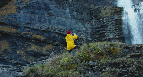 男人独自站在瀑布前拍摄瀑布美景
