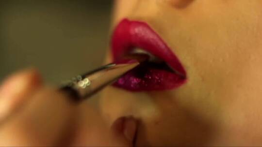 化妆师用刷子在客户的嘴唇上涂上紫色闪光