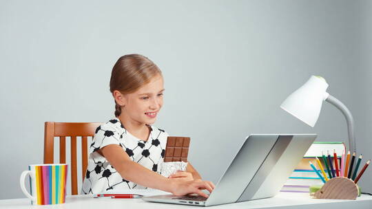 女孩边吃巧克力边玩笔记本电脑视频素材模板下载