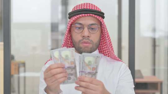 年轻阿拉伯人数钱的肖像视频素材模板下载