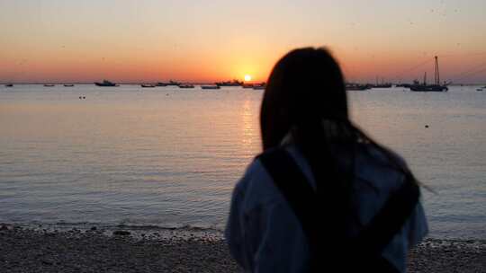 海边一名女子在夕阳下等待