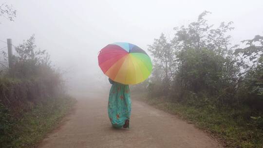 女孩打着雨伞在晨雾中行走