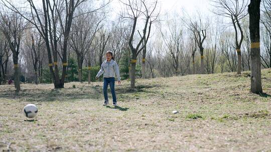 初春在公园草坪上踢足球的中国母女视频素材模板下载