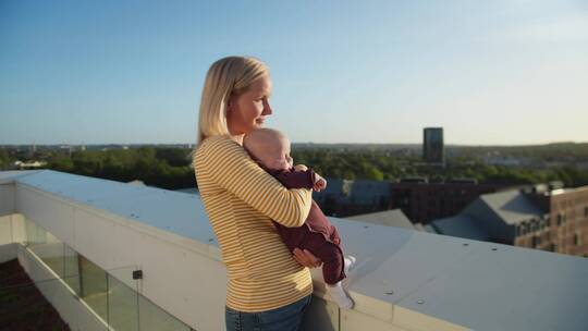 女人抱婴儿在阳台上晒太阳
