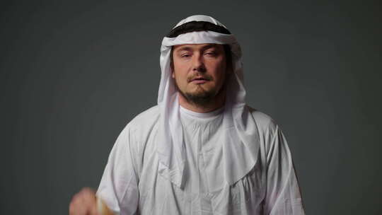 身着传统服装的成功阿拉伯谢赫在灰色背景下手里拿着钱
