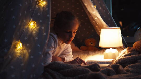 在帐篷里开着台灯看书的女孩