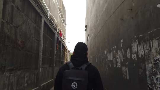 男人背着双肩包在小巷中行走背影