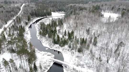 一座横跨白雪覆盖的森林河的桥