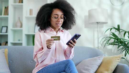 快乐的年轻非裔美国女性在网上购物，在电话