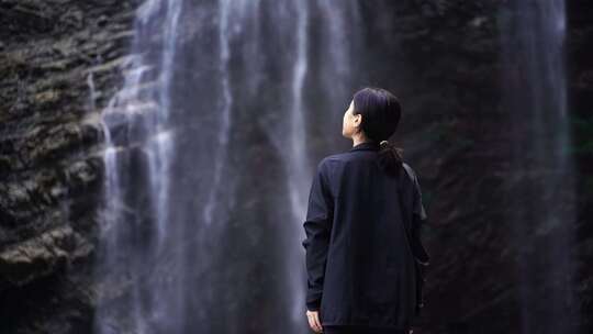 女性人物背影感受亲近自然登顶山峰瀑布水流