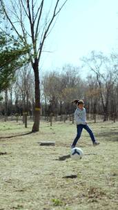 初春在公园草坪上踢足球的中国女孩